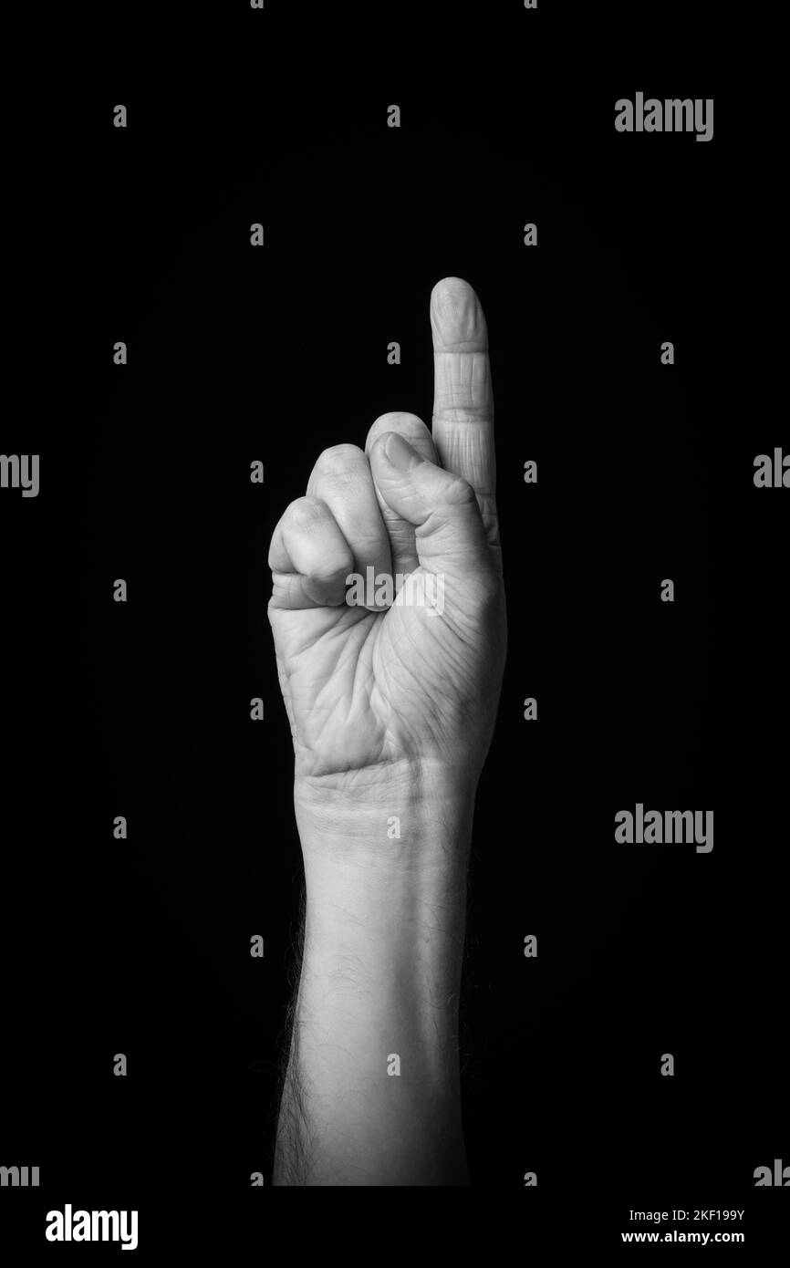 Dramatisches Schwarz-Weiß-Bild einer männlichen Hand, die den arabischen Zeichenbuchstabe 'ب' oder 'Ba' mit der Fingerschrift schreibt, isoliert vor einem dunklen Hintergrund. Stockfoto