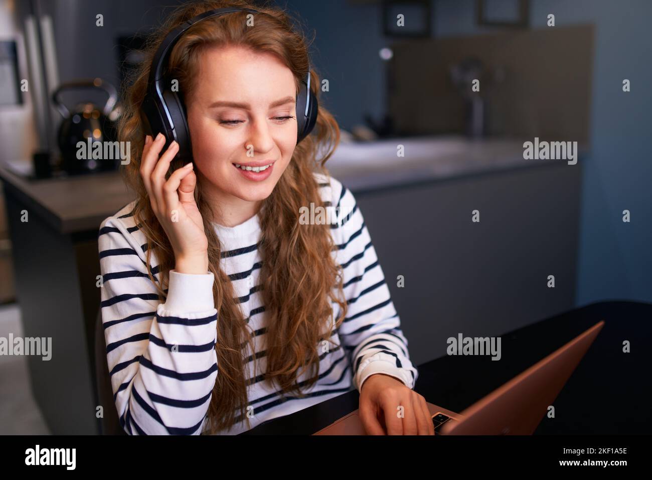 Customer Support Service Call Center Manager spricht, arbeitet von zu Hause aus. Lockige Frau mit Headset, spricht auf einer Videokonferenz mit einer Webcam am Laptop. Jung Stockfoto