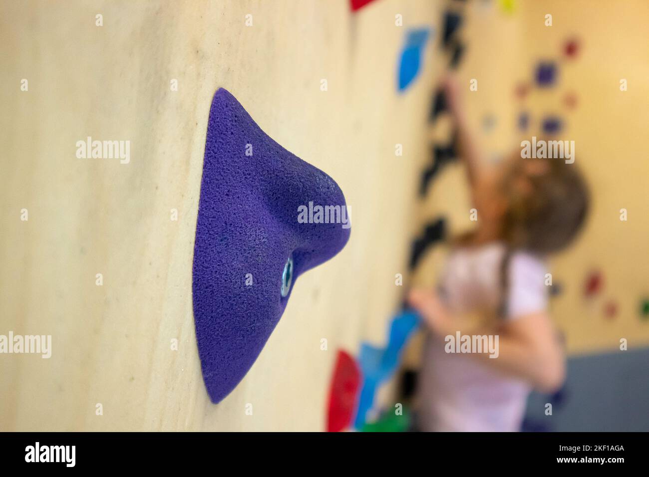 Selektivfokus auf künstlichen Felsgestein. Mädchen machen Felsbrocken, auch bekannt als kostenlose Kletterübung, in den Innenräumen Freizeitaktivitäten. Stockfoto