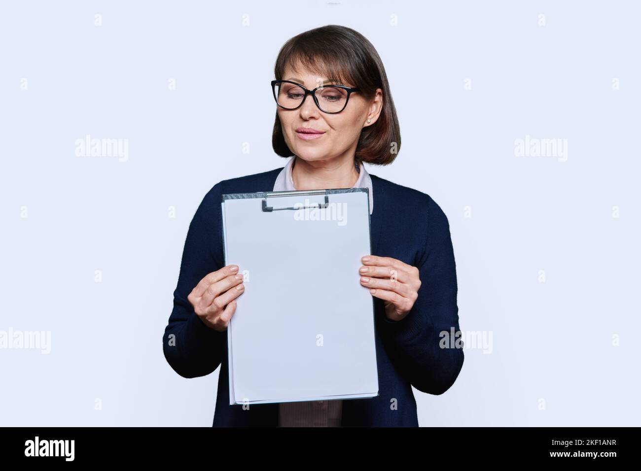 Geschäftsfrau zeigt auf leeren Raum, hält Klemmbrett, weißer Hintergrund Stockfoto