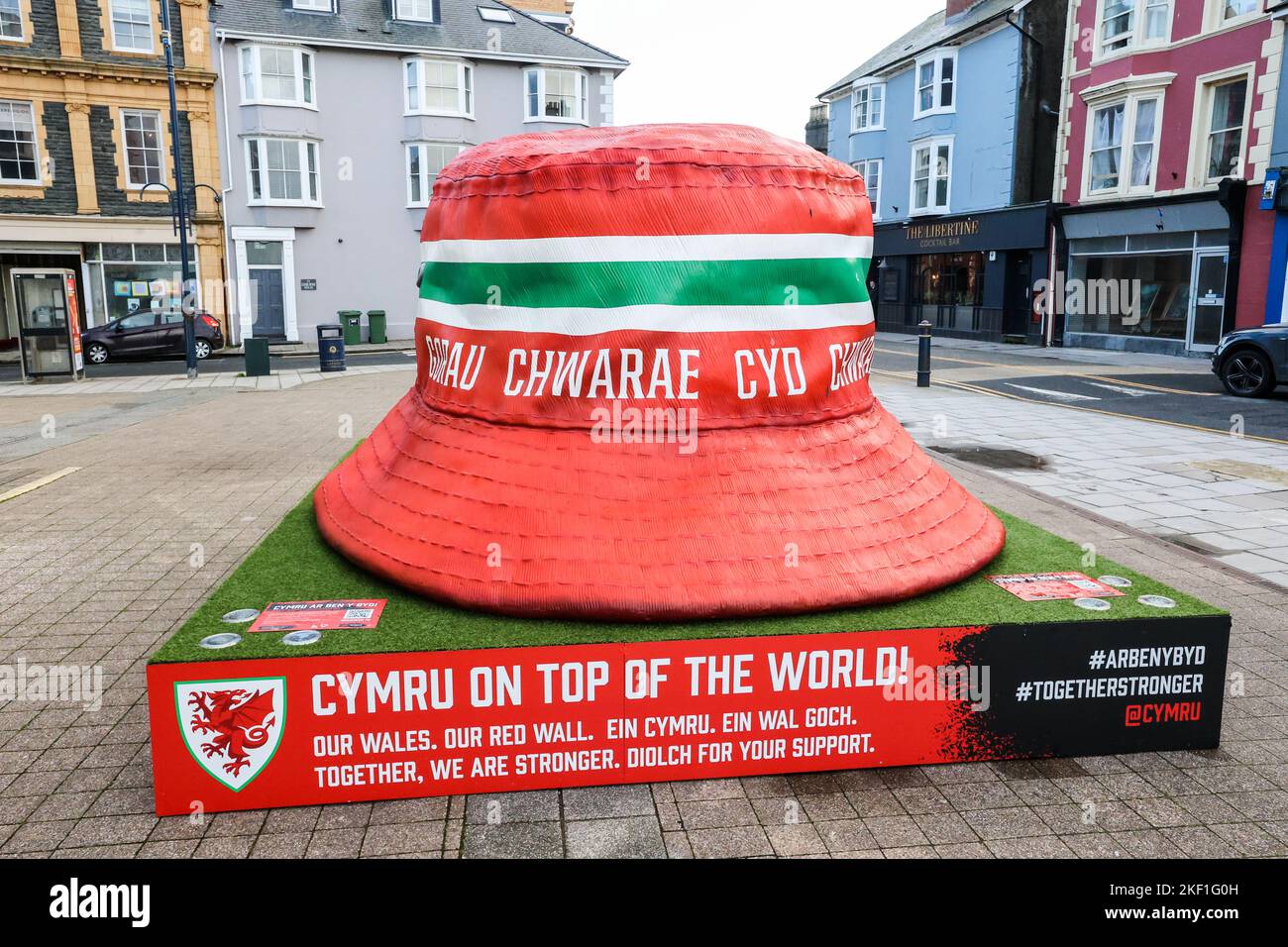 Aberystwyth, Wales, Großbritannien. 15.. November 2022. Riesige kultige walisische Fußballfans mit Hutstruktur, Aberystwyth, Wales, Großbritannien. Groß, 10 Fuß mal 10 Fuß, Kunstinstallation, im Zentrum von Aberystwyth ausgestellt, ist der Eimer Hut zu einem Symbol der Fans der Fußballmannschaft von Wales geworden. Die Statue wurde errichtet, es gibt fünf in walisischen Städten, um die walisische Nationalmannschaft zu feiern, die das Finale der Weltmeisterschaft zum ersten Mal seit 1958 erreicht hat, ein Zeitraum von 64 Jahren, seit sie das letzte Mal bei der Weltmeisterschaft gespielt haben. Kredit: Paul Quayle/Alamy Live Nachrichten Stockfoto