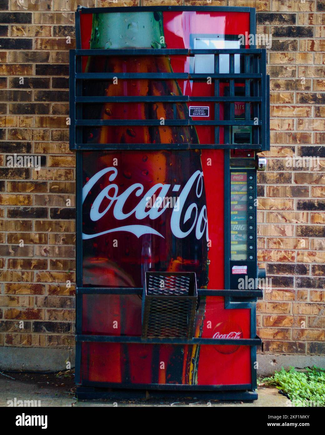 Eine vertikale Aufnahme einer alten Coca-Cola-Maschine mit Käfig. Stockfoto