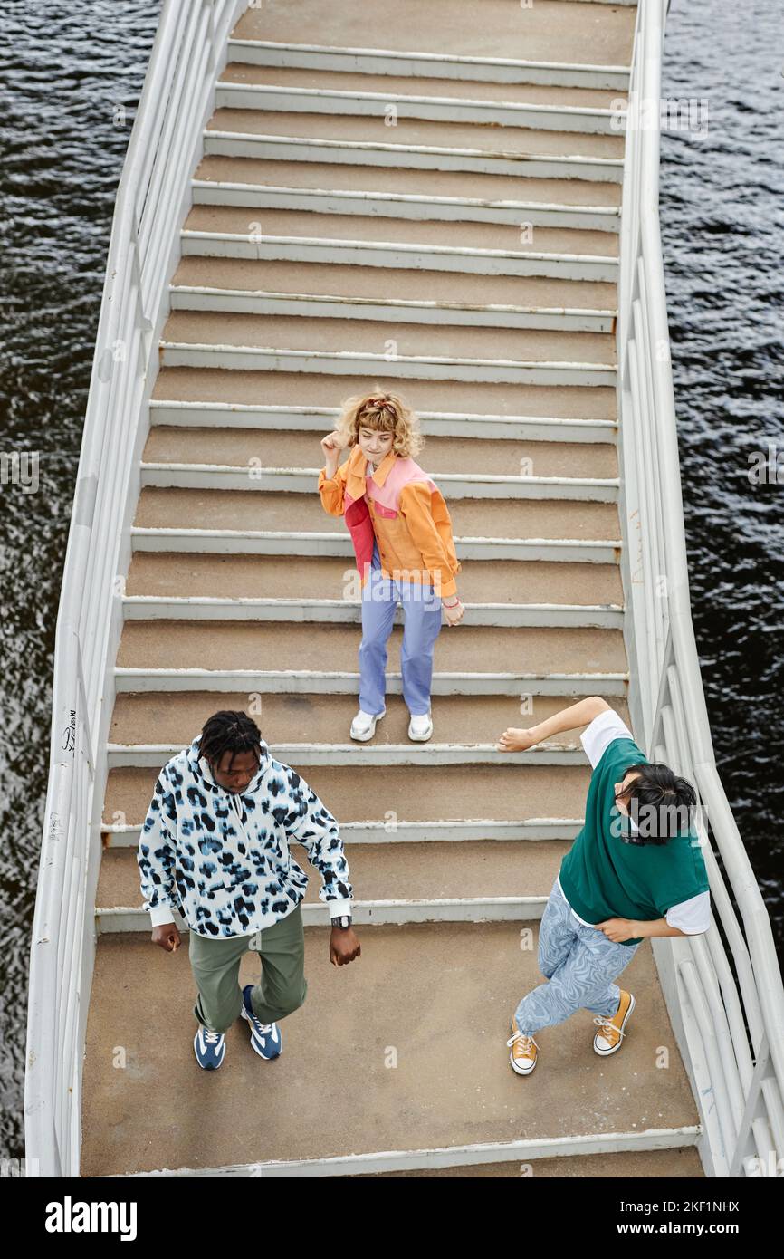 Grafische Draufsicht auf eine Gruppe von jungen Menschen, die auf einer Treppe im Freien tanzen und farbenfrohe Kleidung im Straßenstil tragen Stockfoto