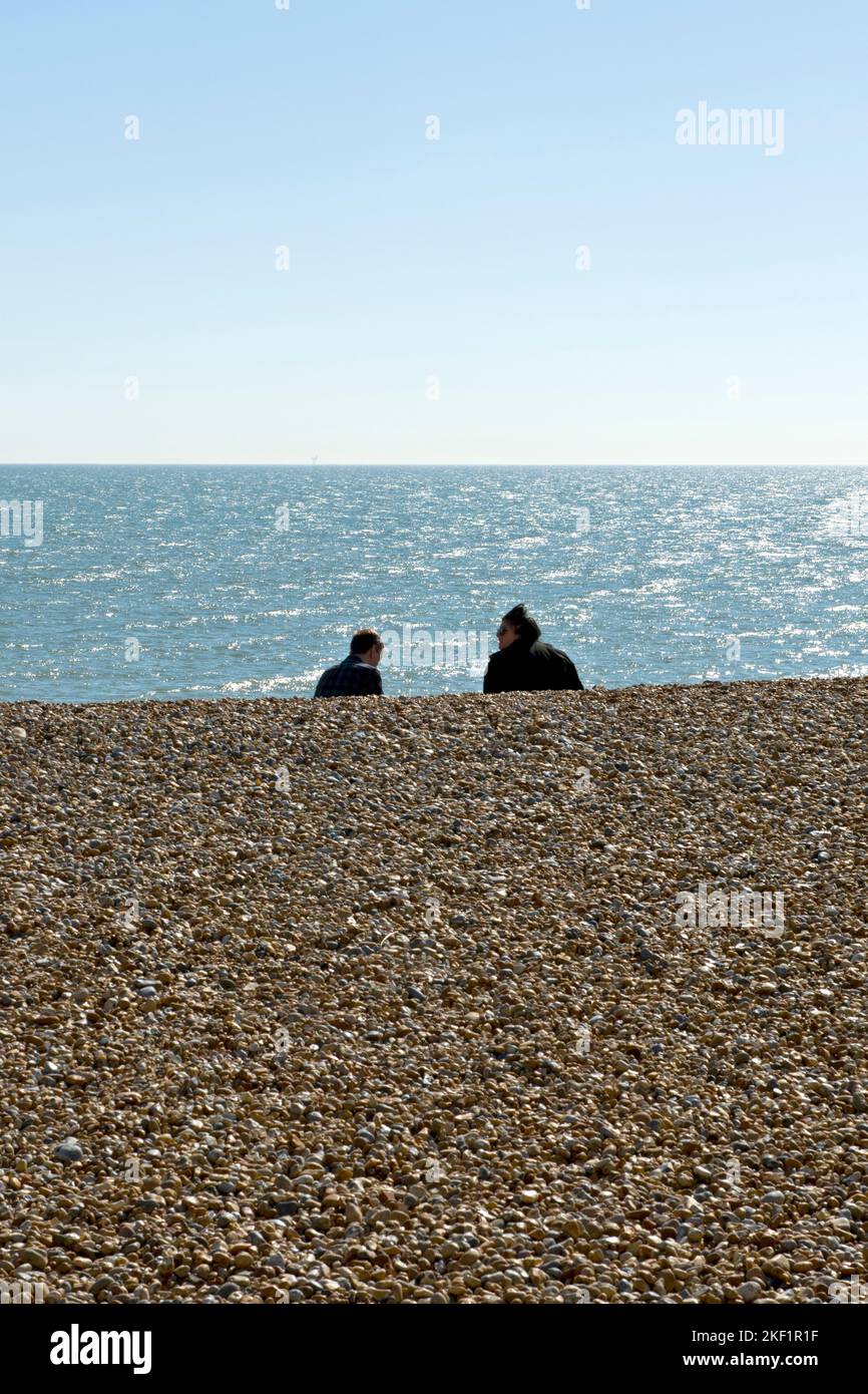 Ein Paar blickt auf das Meer vom Strand in Eastbourne, East Sussex, Großbritannien Stockfoto