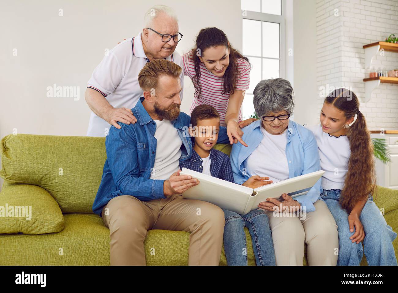 Freundliche Familie Eltern, Kinder, Großeltern suchen Familie Fotoalbum zusammen sitzen auf der Couch. Stockfoto
