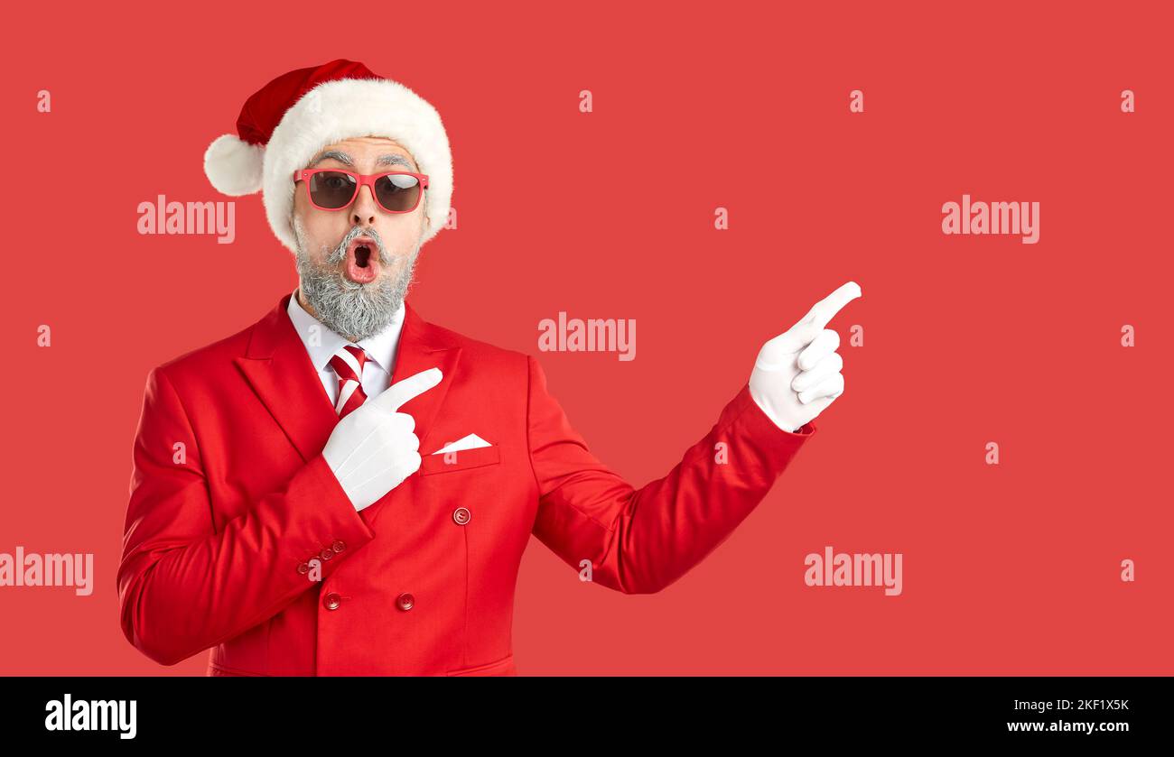Banner mit wundertem, grauhaarigen, bärtigen Mann im Weihnachtsmann-Stil, der auf Copyspace zeigt. Stockfoto