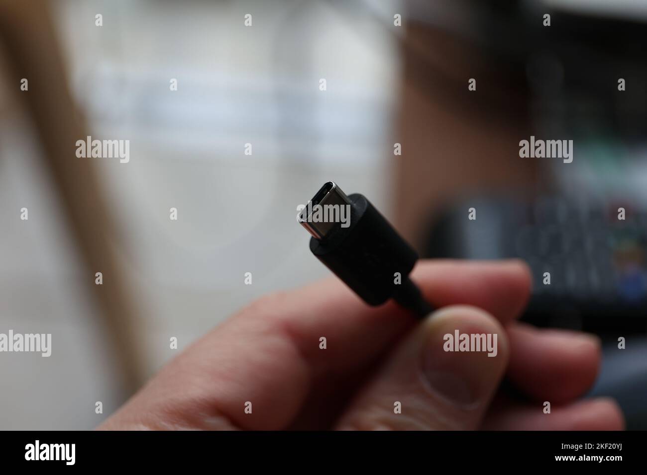 Ein Porträt von jemandem, der ein usb-C-Kabel in den Händen hält. Bereit, ein Telefon oder ein anderes Gerät aufzuladen. Oder stellen Sie eine Verbindung zu einem Computer her, um Daten zu senden oder zu empfangen. Stockfoto