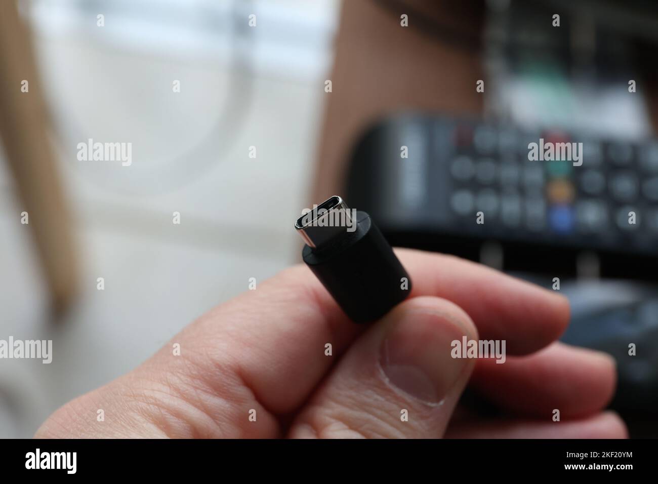 Ein Makroporträt von jemandem, der ein usb-C-Kabel in der Hand hält. Bereit, ein Telefon oder ein anderes Gerät aufzuladen. Oder stellen Sie eine Verbindung zu einem Computer her, um zu senden oder zu empfangen Stockfoto