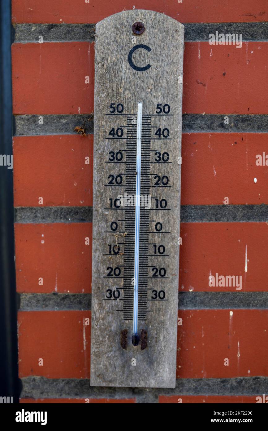 Ein Porträt eines Quecksilberthermometers aus Holz, das die Außentemperatur in Grad Celsius anzeigt und an einer roten Ziegelwand hängt. Die Messeinrichtung Stockfoto