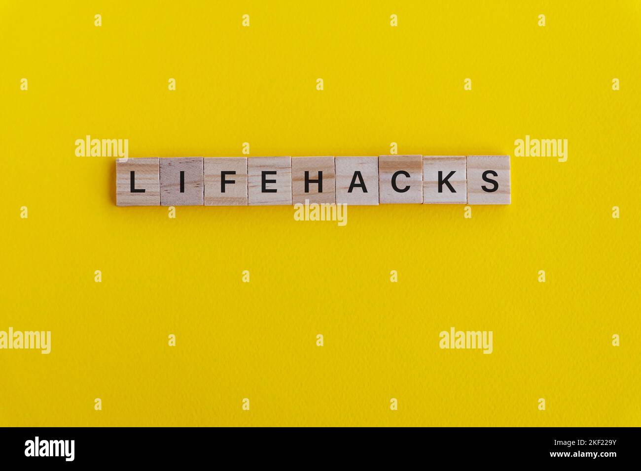 Das Leben hackt die Rechtschreibung auf Holzblock auf gelbem Hintergrund Stockfoto