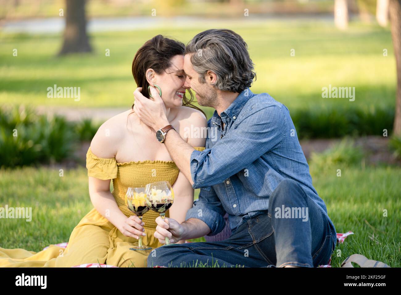 Verliebte Paare bei einem Picknick im Forest Park. Der Mann spielt eine Gitarre für seine Frau. Stockfoto