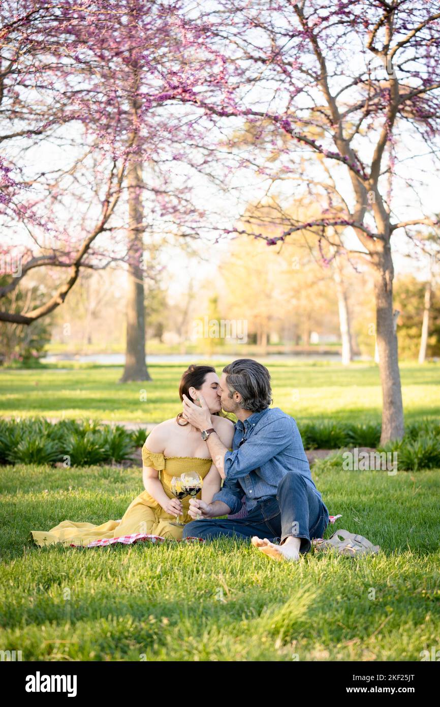 Verliebte Paare bei einem Picknick im Forest Park. Der Mann spielt eine Gitarre für seine Frau. Stockfoto