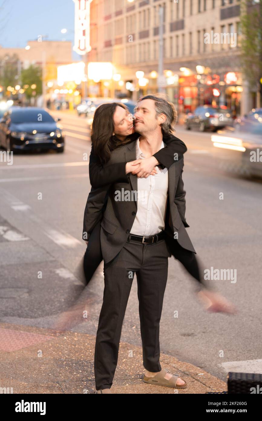 Romantische Fotos eines Paares, das in einer Innenstadt mit Straßenlaternen und Autos im Hintergrund für ein Date unterwegs war. Stockfoto