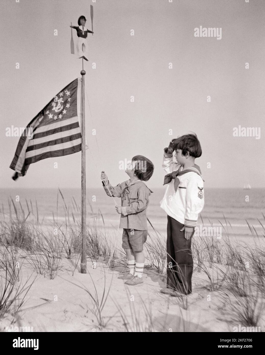 1920S ZWEI JUNGEN STEHEN AUF SANDDÜNE AM STRAND EINER HEBT EINE U. S. YACHT ENSIGN ON FAHNENMAST OTHER BOY SALUTING - J51 HAR001 HARS OCEAN SATISFACTION CELEBRATION BRÜDER, LAND, HEIM VEREINIGTE STAATEN COPY SPACE FREUNDSCHAFT GANZKÖRPERINSPIRATION VEREINIGTE STAATEN VON AMERIKA MÄNNER ZIEHEN GESCHWISTER B&W NORTH AMERICA SUMMERTIME BRUNETTE FREIHEIT NORDAMERIKANISCHES UFER HOCHWINKEL ABENTEUER ERHOLUNG STOLZ STRÄNDE PATRIOT PENNANT POLITIK GESCHWISTER FAHNENMAST VERBINDUNG KONZEPTIONELLE DÜNE PATRIOTISCHE SANDIGE STERNE UND STREIFEN STILVOLLE UNTERSTÜTZUNG ALT RUHM KOOPERATION ENSIGN WACHSTUM JUVENILES PATRIOTISMUS ROT WEISS UND BLAU Stockfoto