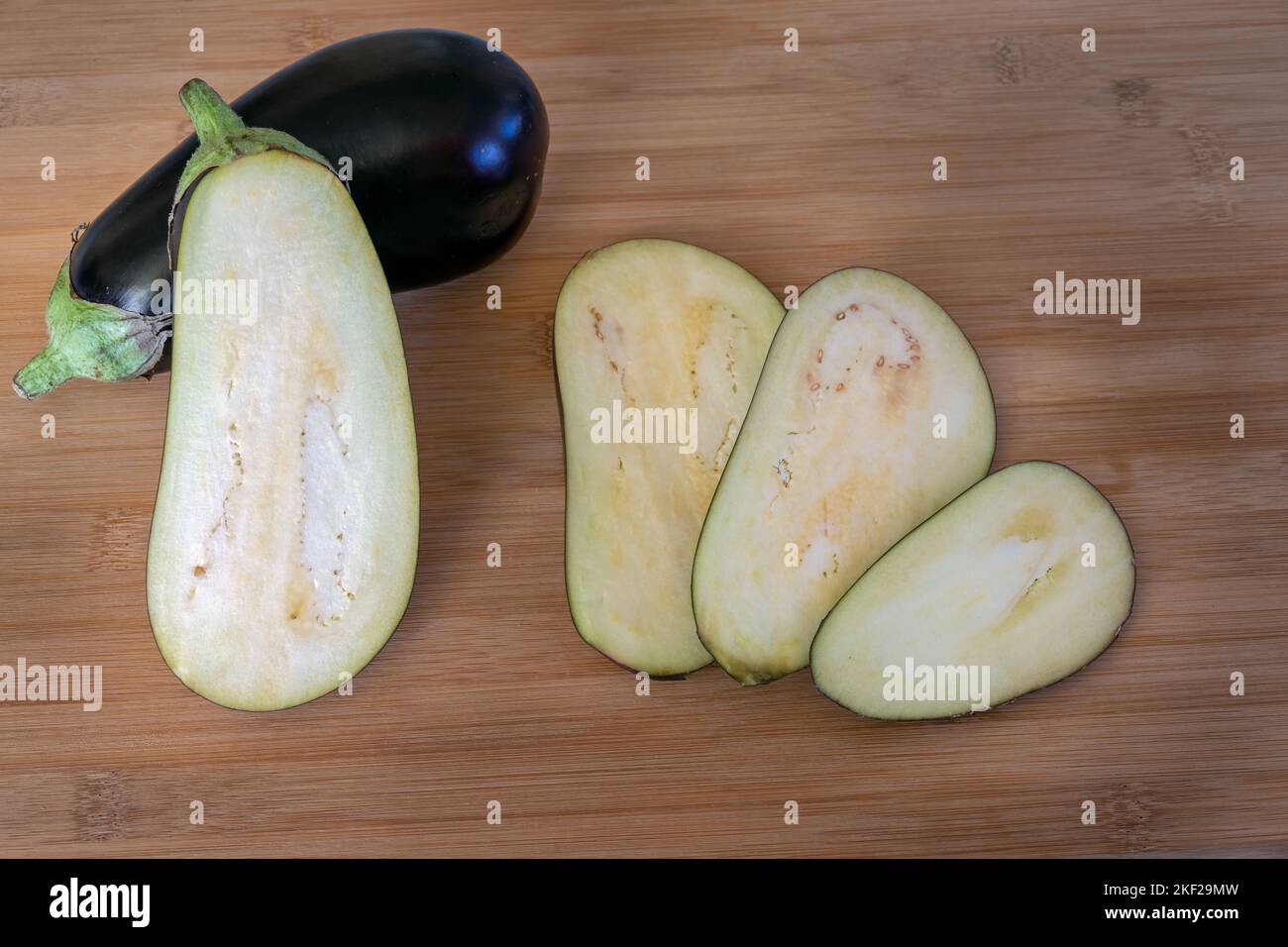 Solanum melongena oder Auberginen- und Auberginenscheiben auf einem Holztisch Stockfoto