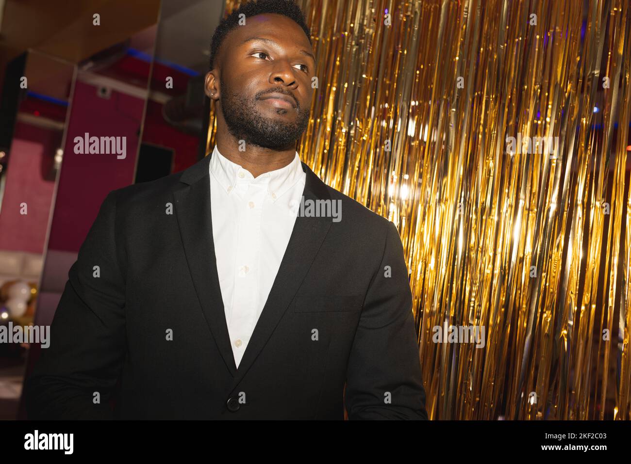 Schlau gekleideter, seriöser afroamerikanischer Portier in einem Nachtclub, der wegschaut Stockfoto