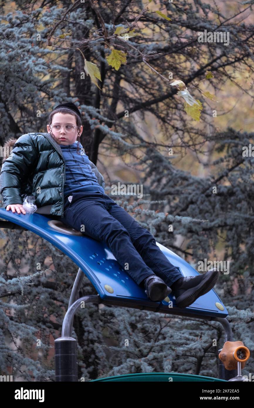 Ein orthodoxer jüdischer Junge sitzt während der Schulpause auf einem Klettergebiet. Auf dem Sobel Playground in Brooklyn, New York. Stockfoto
