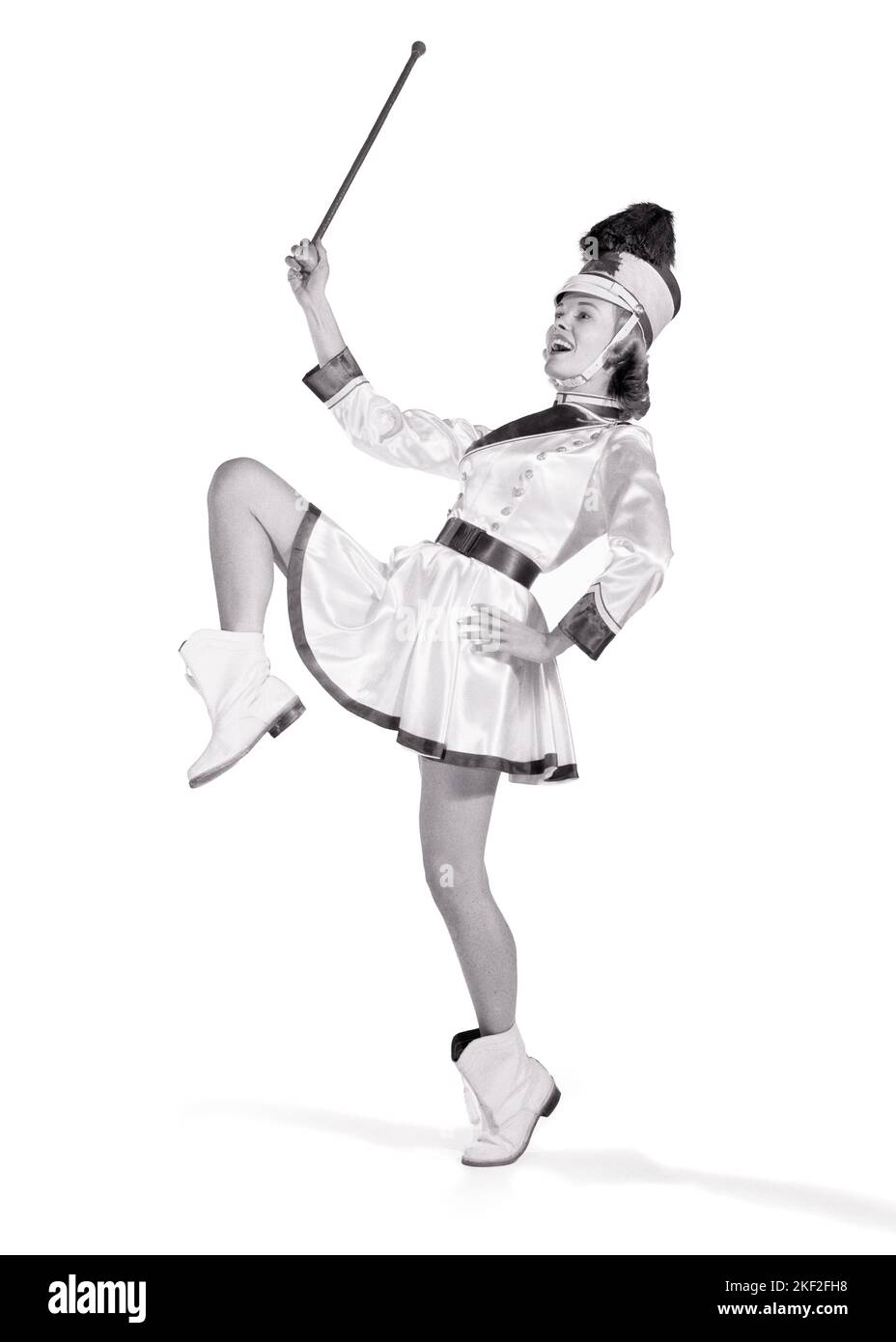 1960S LÄCHELNDES MÄDCHEN MAJORETTE MIT SCHLAGSTOCK TRÄGT BAND UNIFORM MIT PLUMED HUT STIEFEL KURZEN ROCK POSIERT MIT EINEM BEIN ANGEHOBEN - P2279 DEB001 HARS MARCHING CELEBRATION FEMALS STUDIO SHOT COPY SPACE FULL-LENGTH LADIES PERSONS TEENAGE GIRL UNTERHALTUNG CONFIDENCE LEADING SCHWARZWEISS SCHULEN STAFFELSTAB SIEG UNIVERSITÄTEN ERHOLUNG HIGH SCHOOL MÄRZ POSIERT HIGH SCHOOLS HOCHSCHULBILDUNG STÜRZTE TEENAGERSCHULEN DEB001 MAJORETTE JUGENDLICHE JUNG ERWACHSENE FRAU SCHWARZ UND WEISS KAUKASISCHEN ETHNIE HOHE TRITTBRIGKEIT MARCHER ALTMODISCHE PARADEN Stockfoto