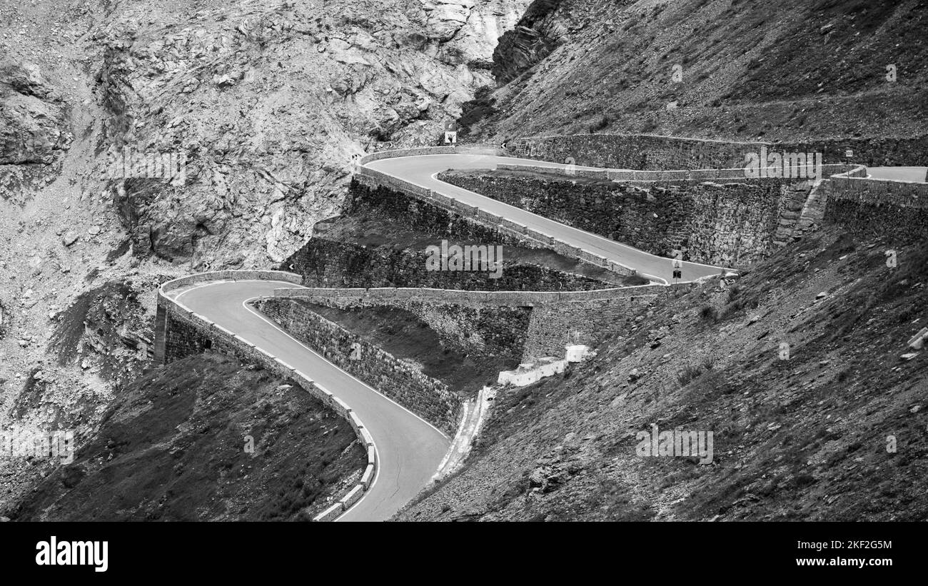 Serpentinen der alpinen Bergstraße zum Stilfserjoch, Italienisch: Stilfserjoch, Südtirol, Italienische Alpen, Italien. Schwarzweiß-Bild. Stockfoto