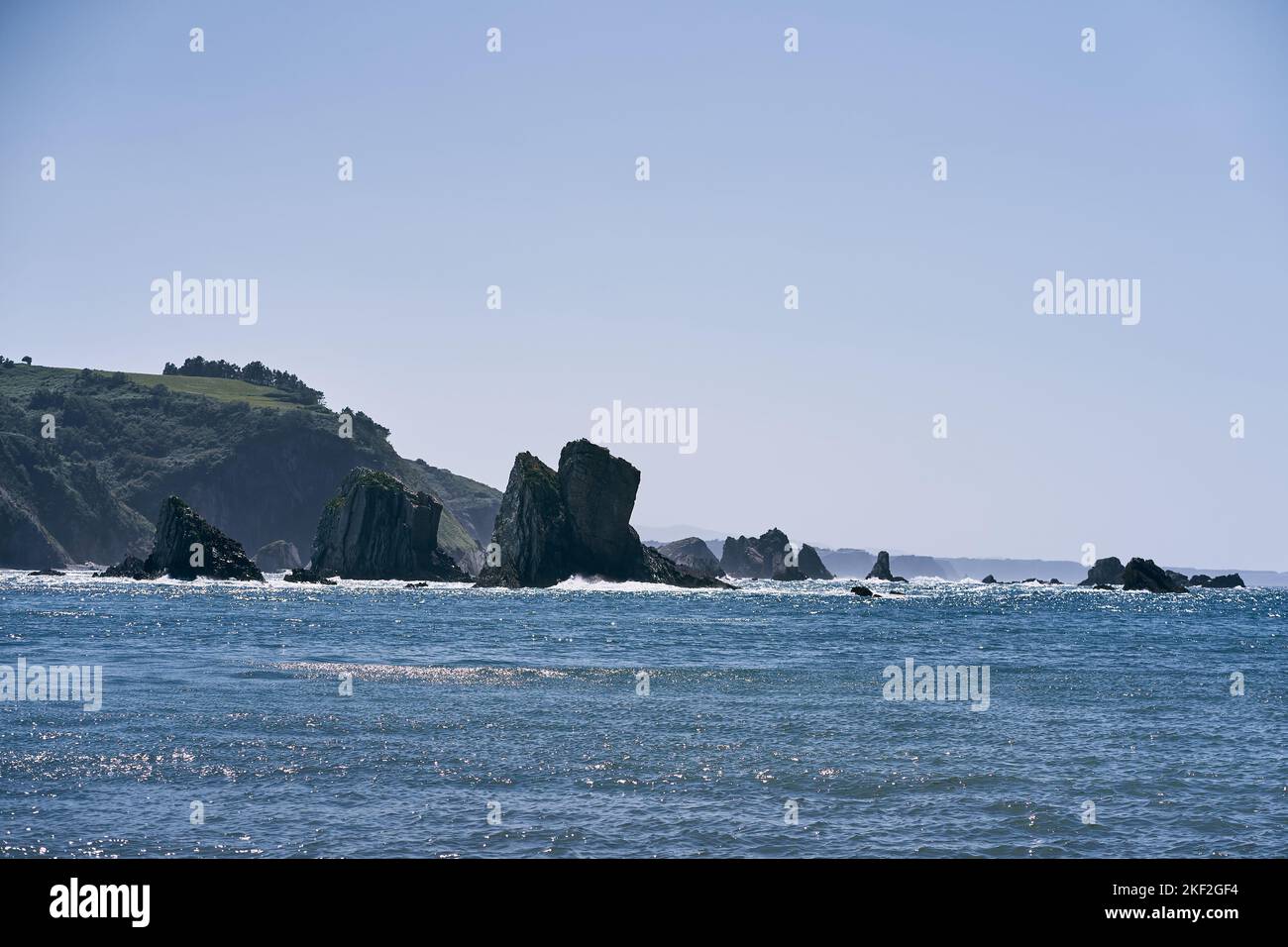 Landschaft des kantabrischen Meeres von der Sonne beleuchtet mit großen Felsen in der Nähe der Klippen in einem ruhigen und einsamen Ort, asturien, spanien Stockfoto