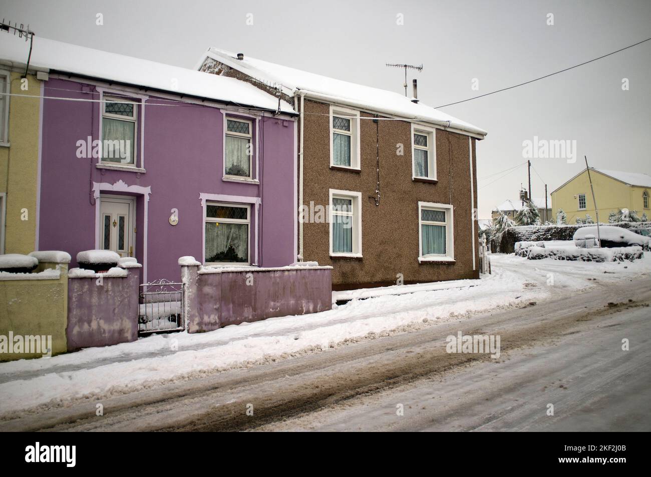 Winterszene in Merthyr Tydfil. Farbenfrohe Häuser im Schnee mit einem silbernen Himmel im Hintergrund. Stockfoto