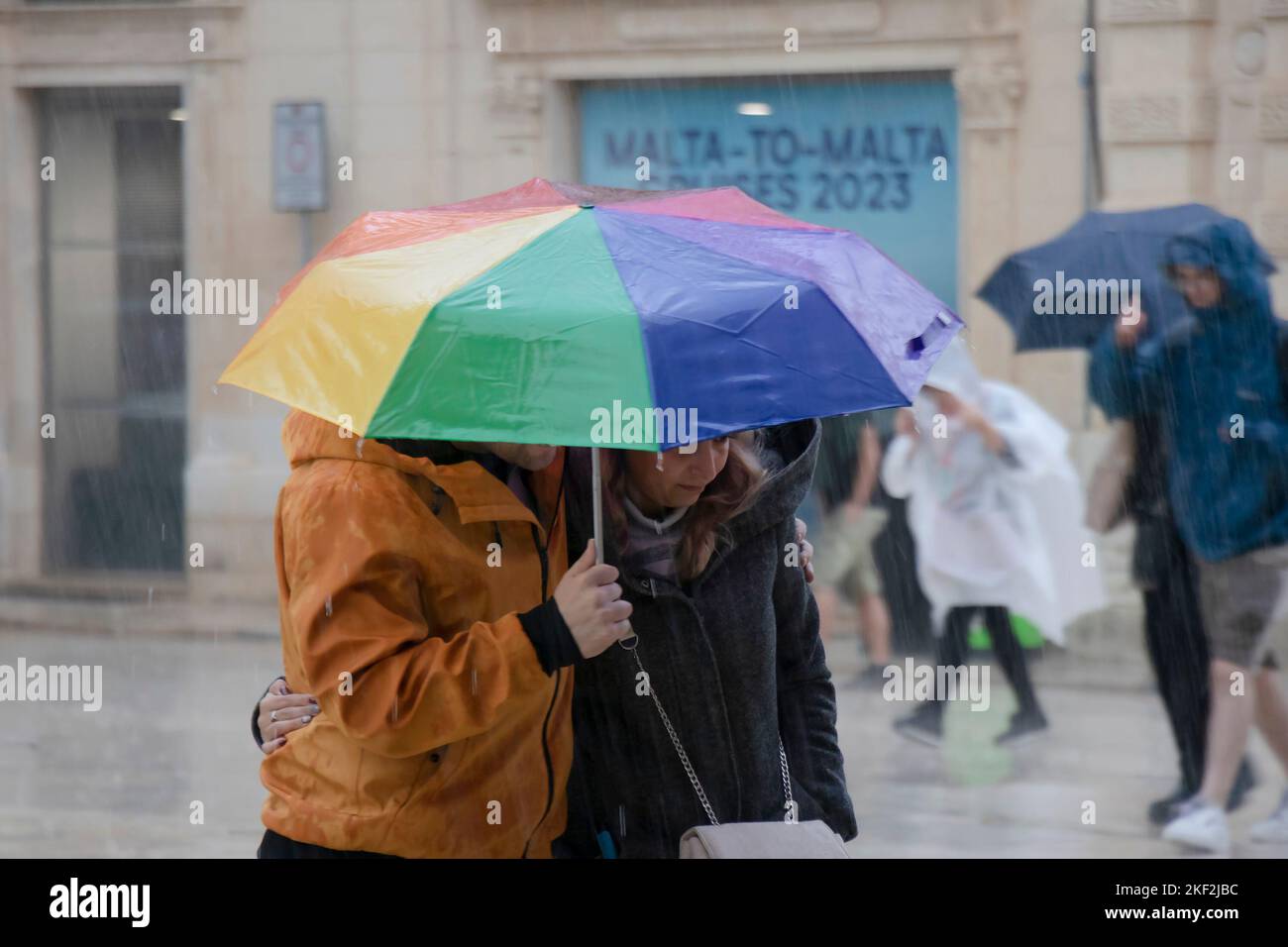 Valletta, Malta - 12. November 2022: Menschen, die an einem regnerischen Tag unter Sonnenschirmen spazieren Stockfoto