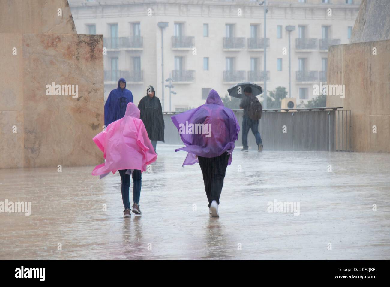 Valletta, Malta - 12. November 2022: Menschen, die Regenponchos und Regenschirme tragen, wandern an einem regnerischen Tag Stockfoto