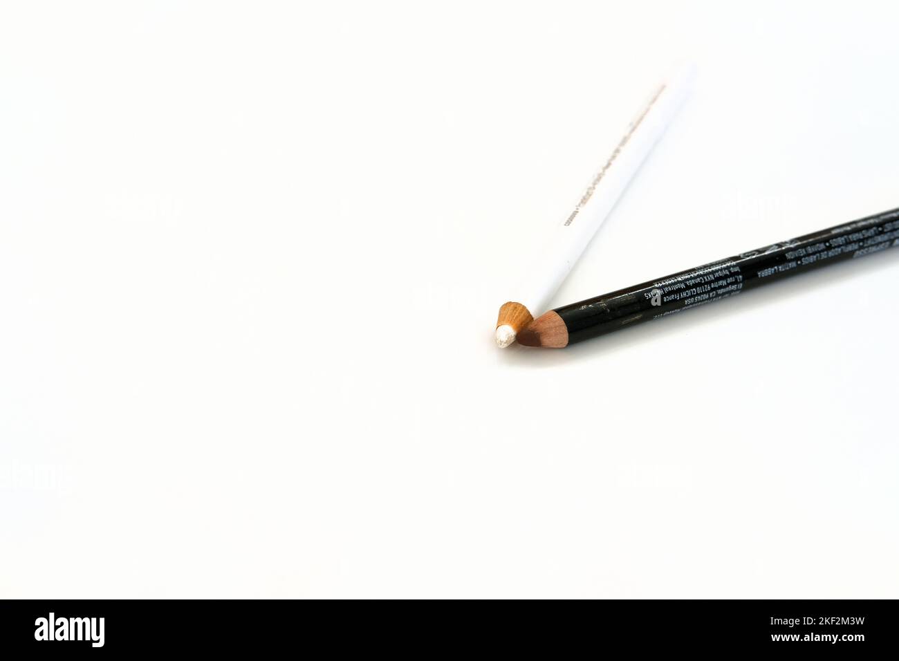 Brauner Lippenstift und weißer Eyeliner-Bleistift auf weißem Hintergrund; Augen-Make-up und Kosmetik. Stockfoto