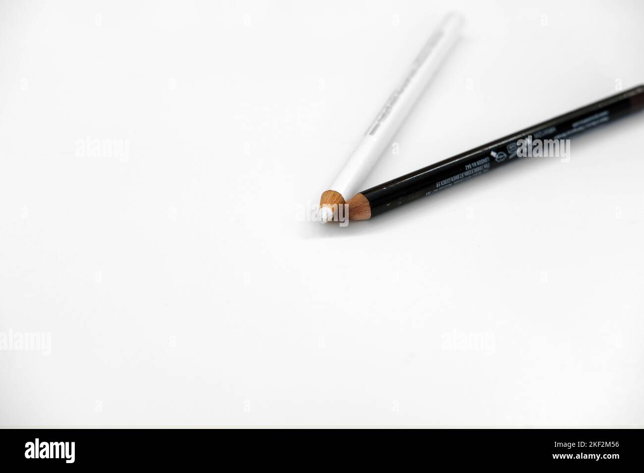 Brauner Lippenstift und weißer Eyeliner-Bleistift auf weißem Hintergrund; Augen-Make-up und Kosmetik. Stockfoto