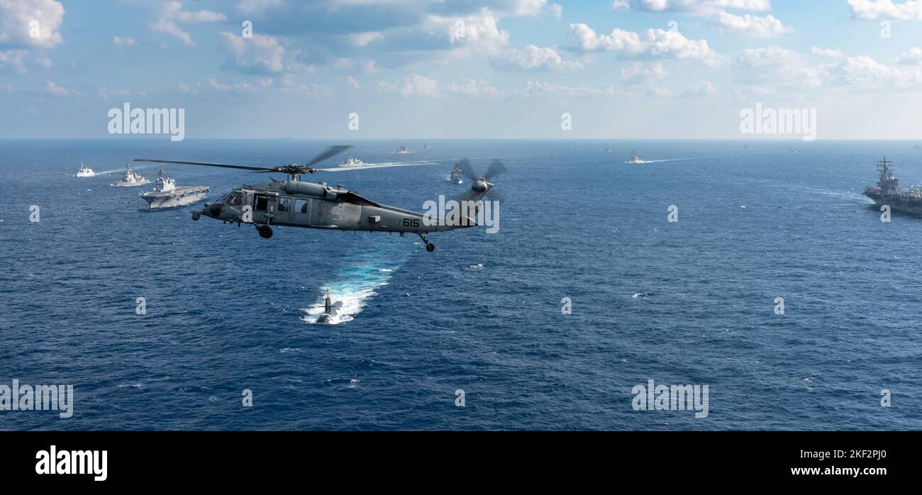 221114-N-DW158-1183 PHILIPPINISCHES MEER (NOV 14, 2022) ein MH-60s Seahawk, der an den Golden Falcons of Helicopter Sea Combat Squadron (HSC) 12 befestigt ist, fliegt während des Keen Sword 23 im philippinischen Meer über eine Formation von Schiffen der US Navy, der Japan Maritime Self-Defense Force (JMSDF), der Royal Navy, der Royal Australian Navy und der Royal Canadian Navy, Nov. 14. Keen Sword ist eine zweijährige, gemeinsame und bilaterale Übung zur Außendienstausbildung mit US-Militär und JMSDF-Mitarbeitern, die darauf ausgelegt ist, die Bereitschaft und Interoperabilität zu erhöhen und gleichzeitig die eiserne Allianz zwischen Japan und den USA zu stärken. USS Ronald Reagan (CVN 76) Stockfoto