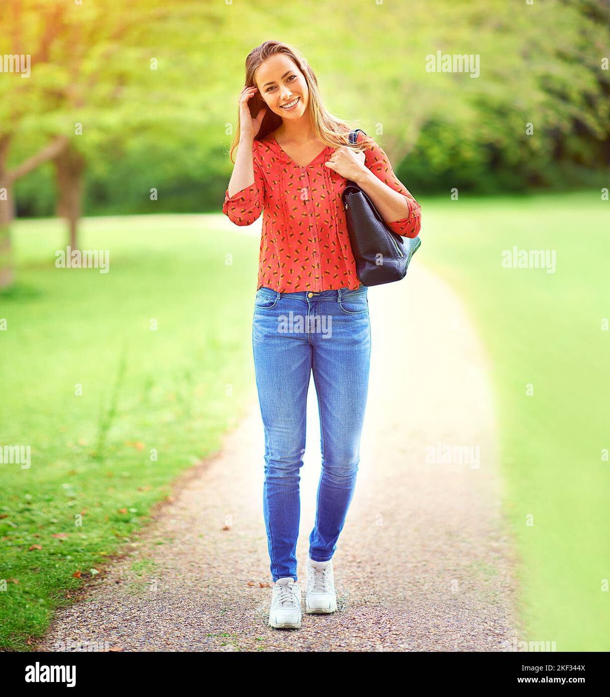 Im Freien zu sein, bringt mir immer ein Lächeln ins Gesicht. Eine junge Frau auf einem Spaziergang durch den Park. Stockfoto