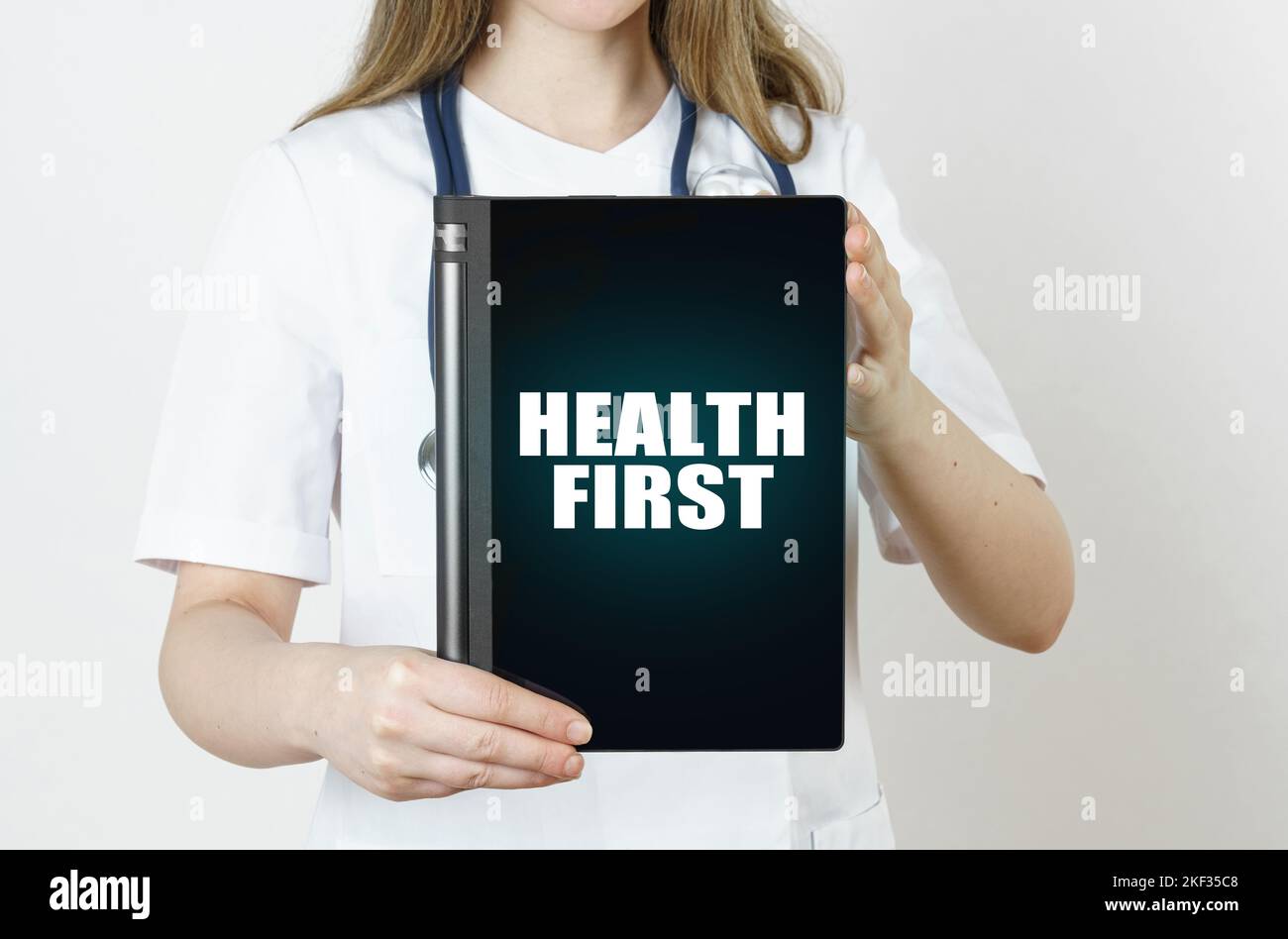Medizin und Gesundheitskonzept. Der Arzt hält eine Tablette mit der Aufschrift - GESUNDHEIT ZUERST Stockfoto