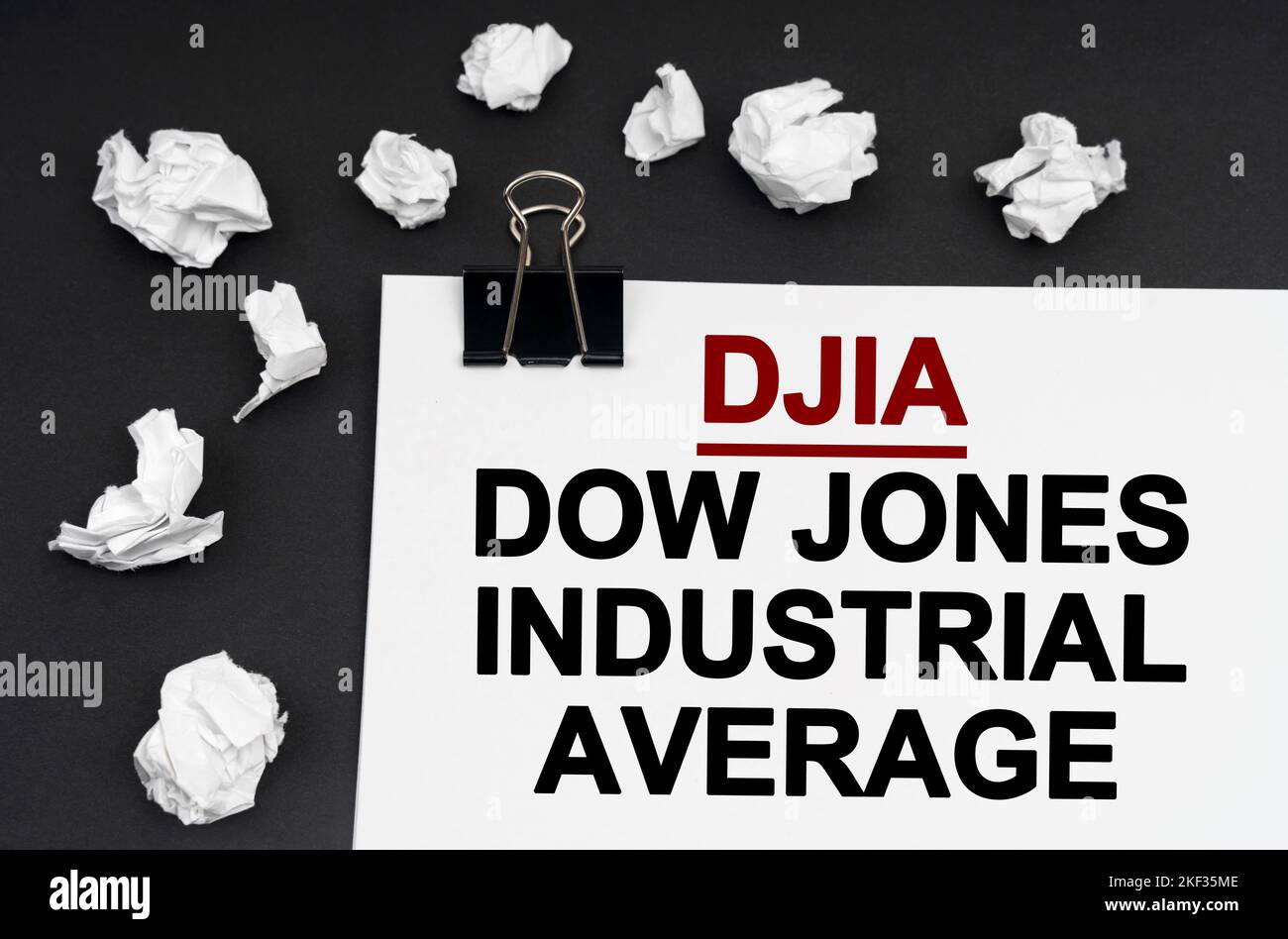 Industriekonzept. Auf schwarzem Hintergrund befinden sich zerknitterte Papierstücke und Papier mit der Aufschrift Dow Jones Industrial Average Stockfoto