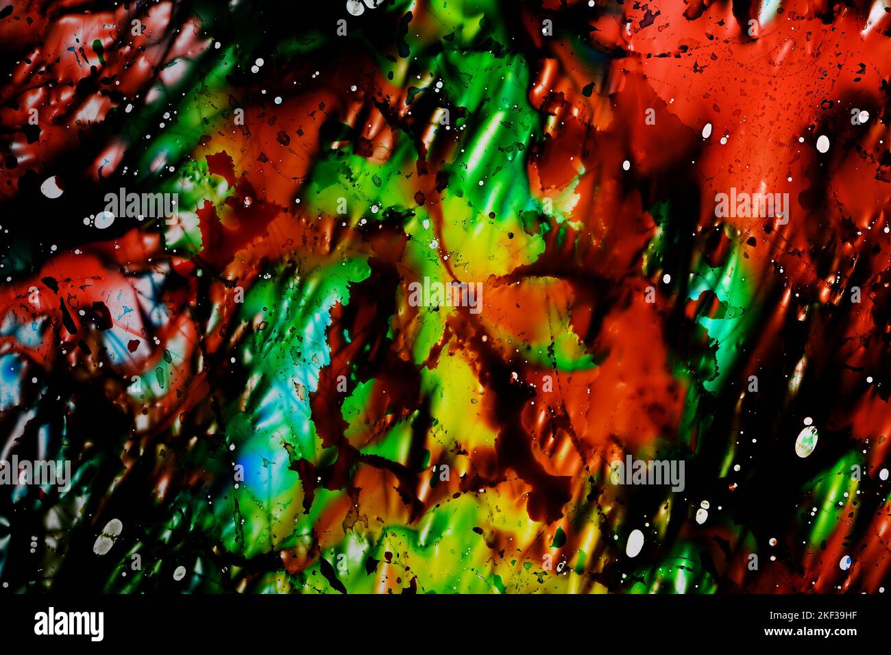 Eine lebhafte chaotische abstrakte Mischung aus blauen, grünen, gelben und roten Lebensmittelfarbstoffen auf einer dünnen Folie aus leicht zerbrochenem Kunststoff auf einer Leuchtkasten Stockfoto