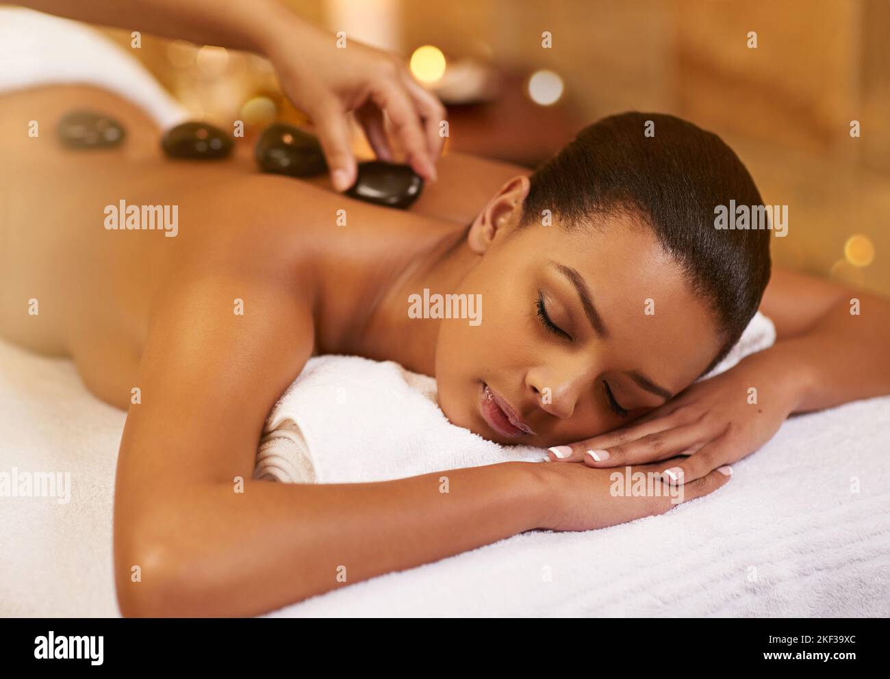 Eine junge Frau genießt eine Latontherapie im Spa. Stockfoto