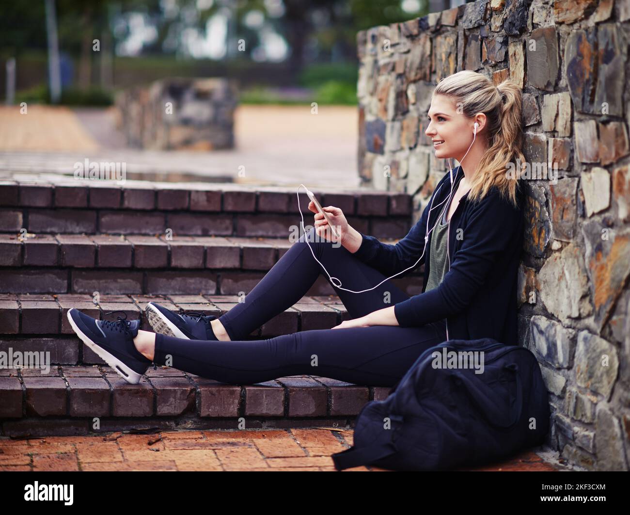 Musik motiviert sie. Eine sportliche junge Frau, die draußen Musik hört. Stockfoto