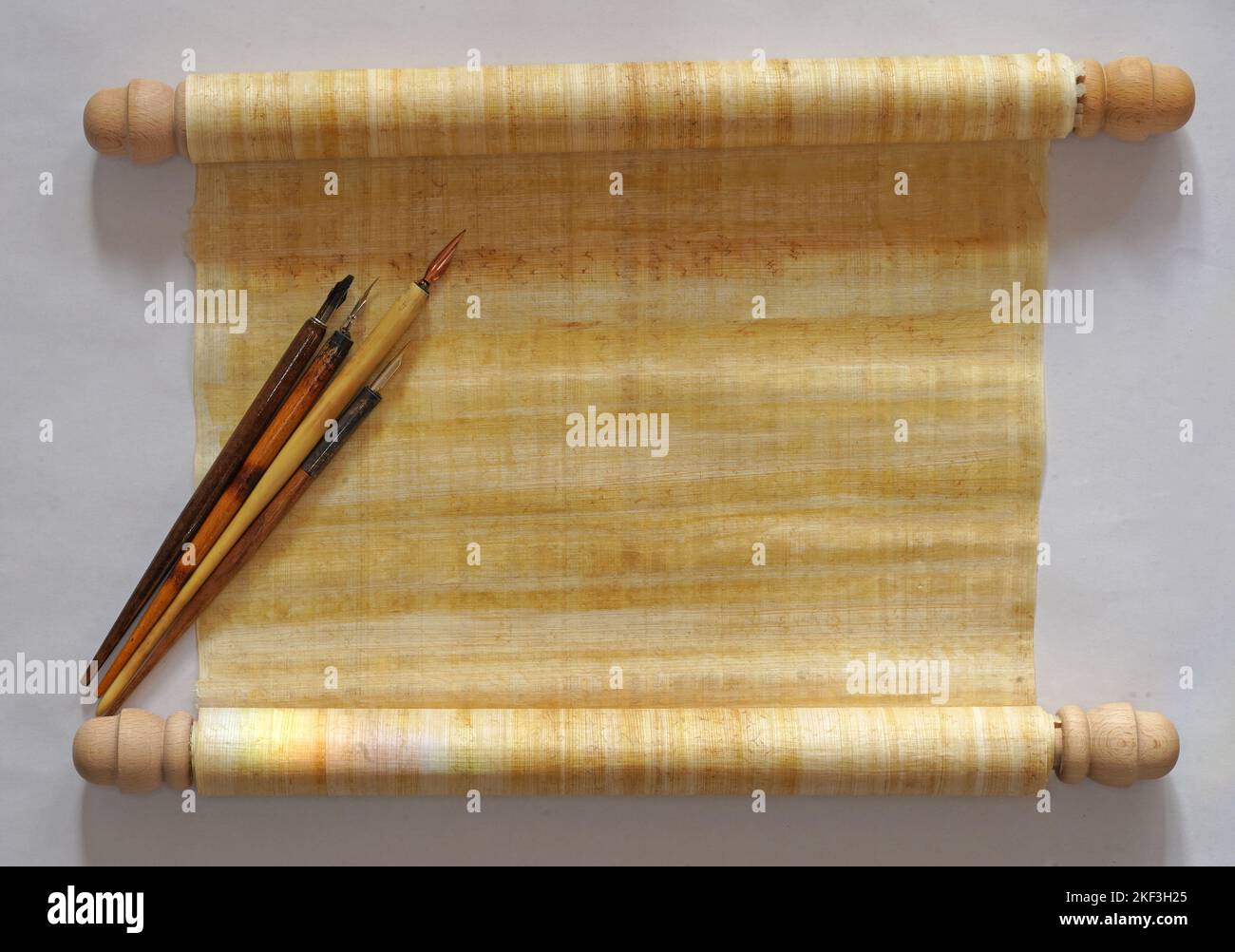 Eine Papyrus-Schriftrolle mit vier altmodischen Schreibstiften mit einem Halter darauf. Ansicht der oberen Tabelle. Mit Platz für Ihren eigenen Text Stockfoto