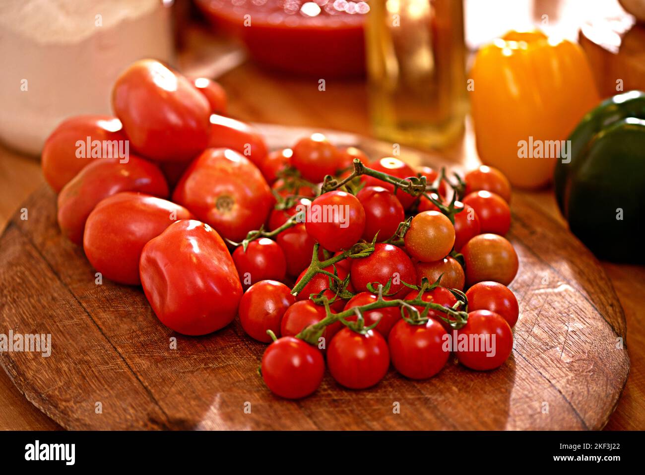 Verlockende Tomaten. Eine Pflaume und Kirschtomaten auf einem Tisch in einer Küche. Stockfoto