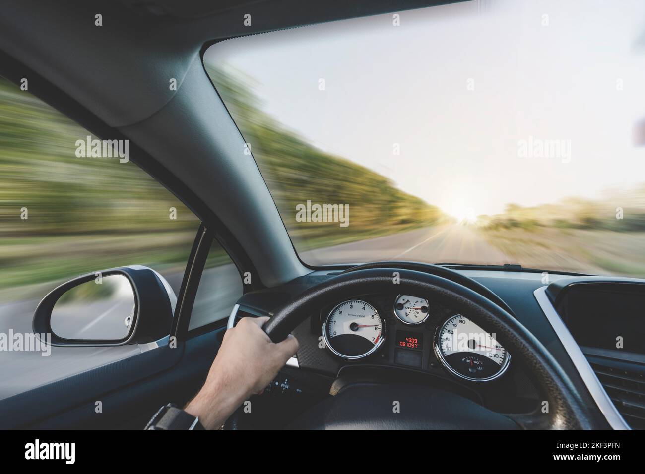 Man Hand fahren Auto. Fahren mit hoher Geschwindigkeit auf der Autobahn. Aus Sicht der ersten Person. Eine Männerhand hält das Lenkrad des Autos. Bewegungsunschärfe Stockfoto