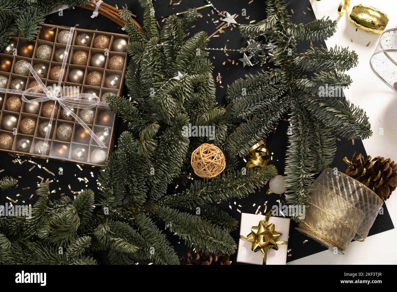 Tannenkranz und Weihnachtsdekor auf schwarz-weißem Hintergrund. Vorbereitungen für Weihnachten, Postkarte, Weihnachtskugeln, Geschenkboxen, Bänder. Flaches Lay, eleganter Stil, Urlaub. Stockfoto