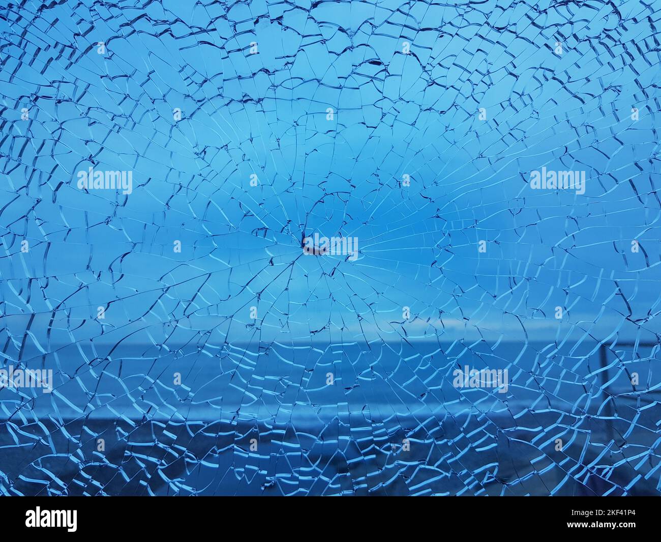 Zerbrochenes Glas mit Rissen. Abstrakt geknackt Schuss Fenster auf blau Stockfoto