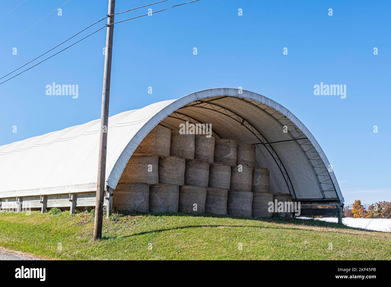 Runde Heuballen, die in einer Reifendscheune im ländlichen Ohio unter Deckung gelagert werden. Stockfoto
