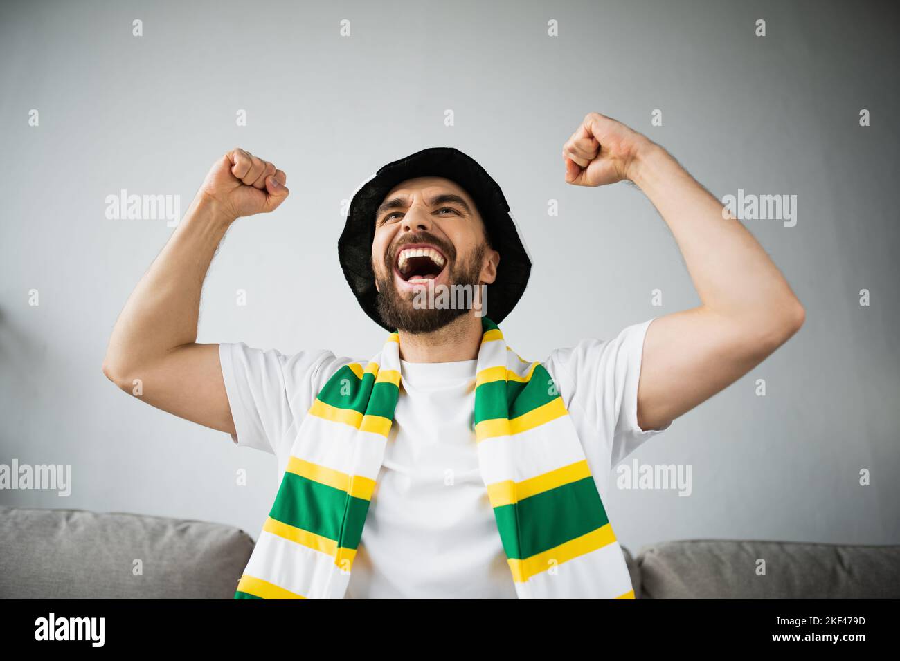 Aufgeregt Mann in Fan Hut und steif Schal feiern beim Betrachten der Meisterschaft, Stock Bild Stockfoto