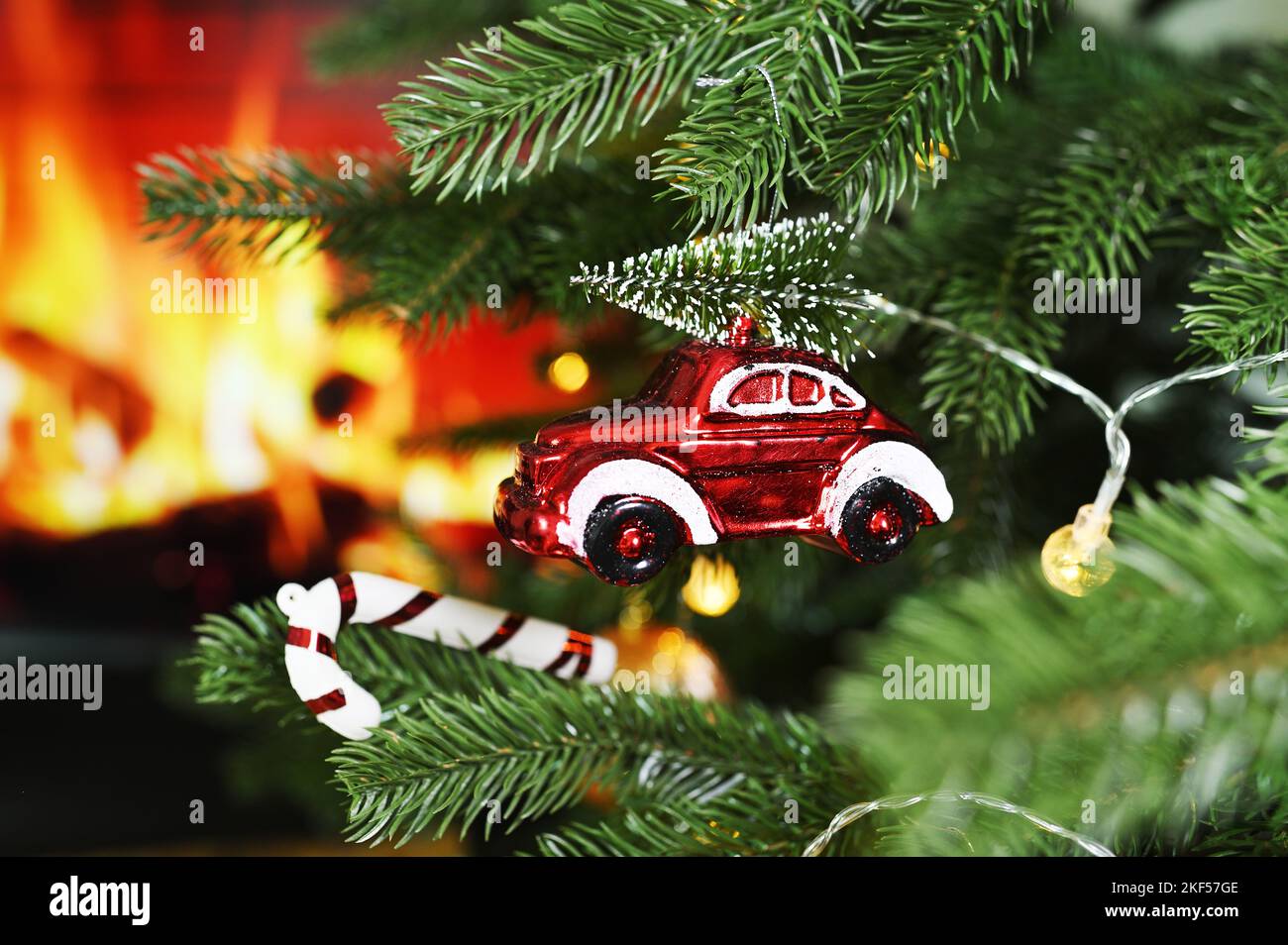 Weihnachtsbaum Spielzeug kleines rotes Oldtimer mit einem Weihnachtsbaum auf dem Dach vor dem Hintergrund eines Kamins. Stockfoto
