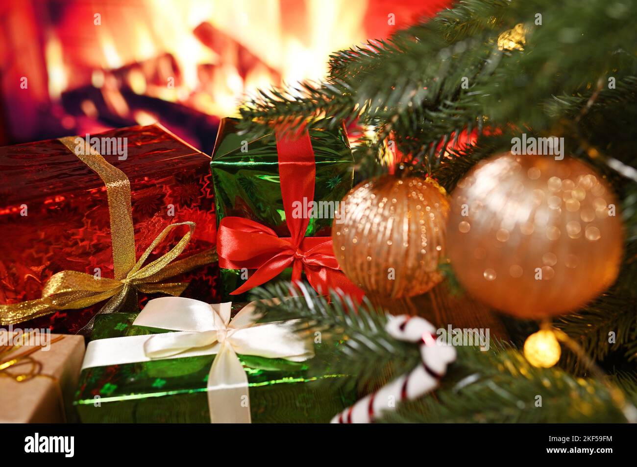 Viele Kisten mit Weihnachtsgeschenken auf einem Holztisch vor dem Hintergrund eines Weihnachtsbaums und eines Kamins. Stockfoto