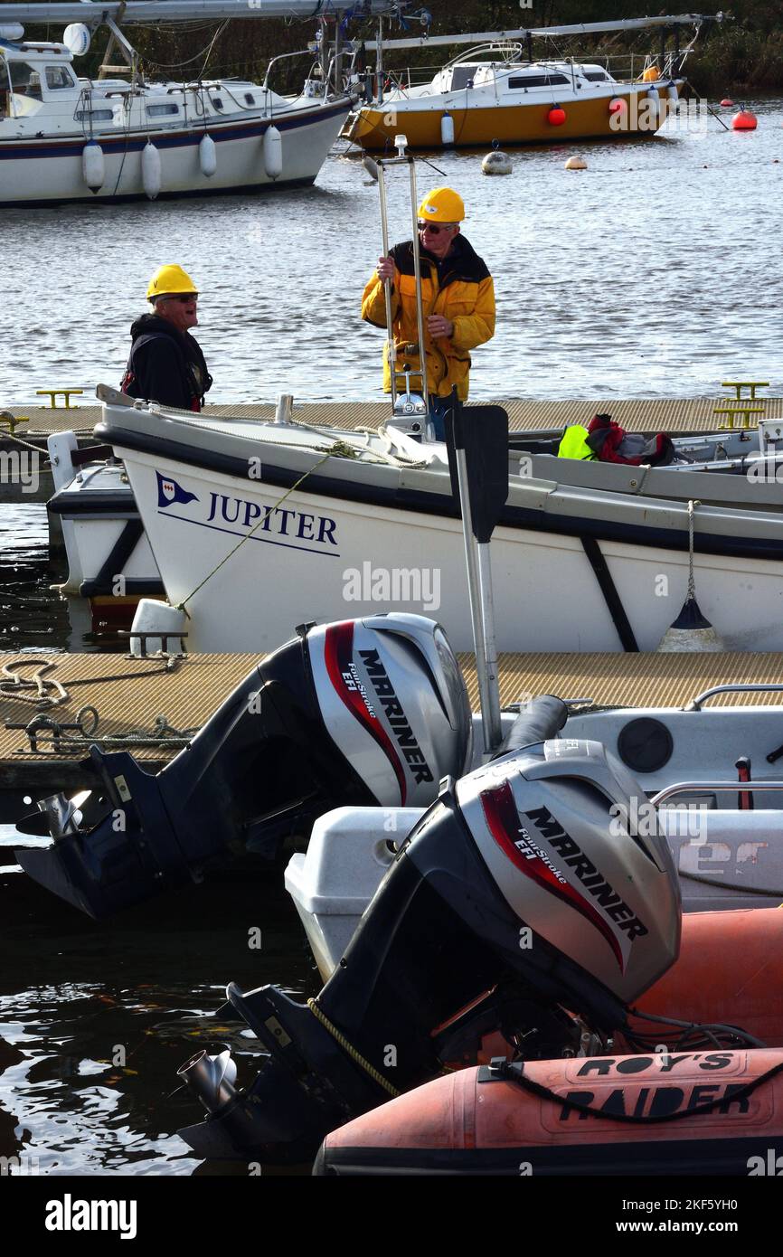 Bootsanlegestelle am Flussufer mit Außenbordmotoren und Wartungspersonal Stockfoto