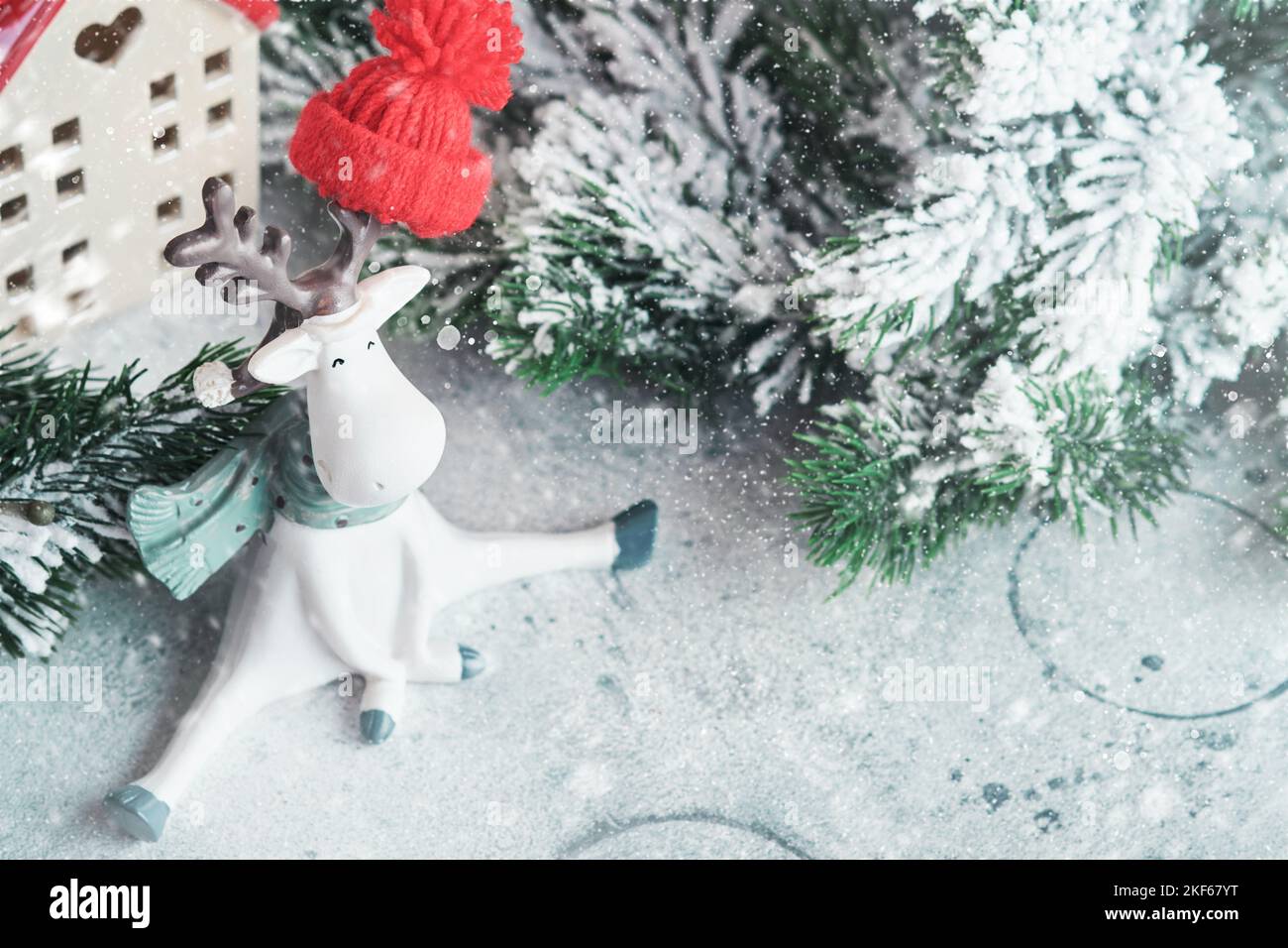 Neujahrskarte. Weihnachten. Zwei Häuser in weißem Schal mit Christbaumzweigen im Schnee, lustigen Rentieren und schönem Bokeh gewickelt. Neujahr Stockfoto