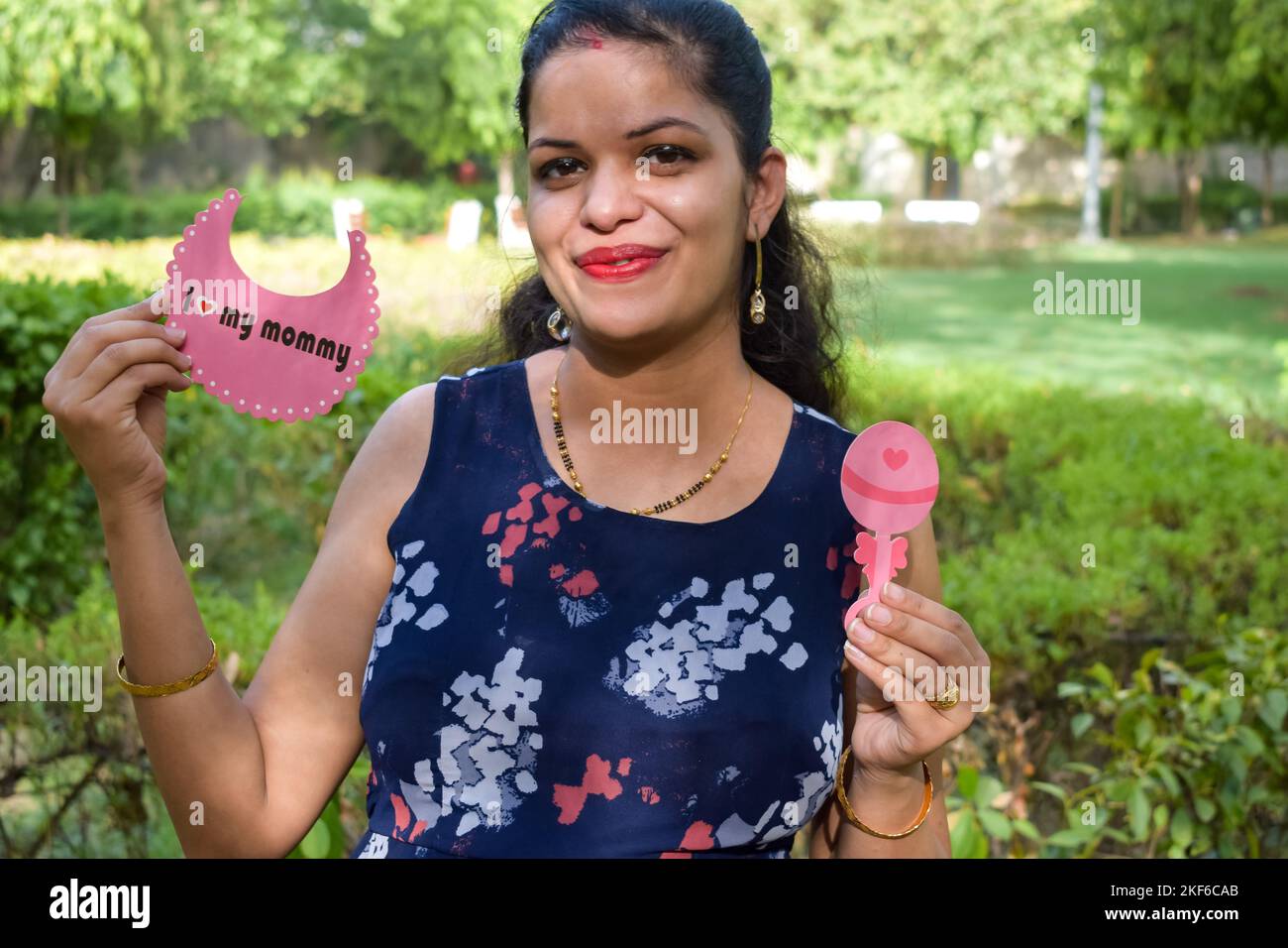 Indisches Paar posiert für Mutterschaft Baby Shoot. Das Paar posiert auf einem Rasen mit grünem Gras und die Frau fällt in Lodhi Garde ihren Babybauch aus Stockfoto