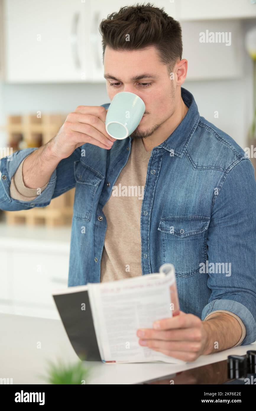 Junger Mann trinkt einen Kaffee und liest ein Buch Stockfoto