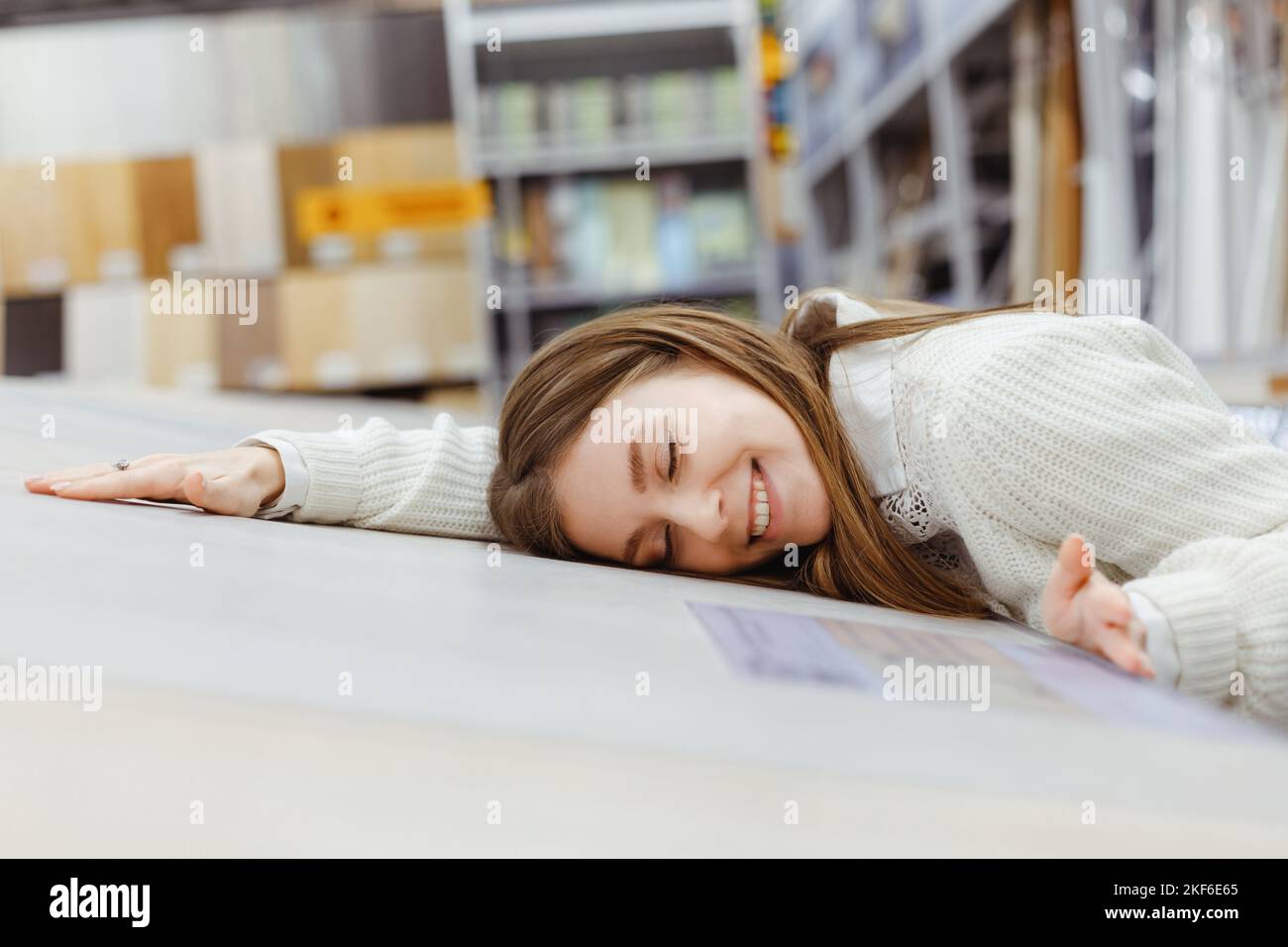 Frau, die Laminatboden für die Renovierung von Zuhause wählt. In Liebe zu natürlichen Materialien, taktiles qualitatives Material Stockfoto